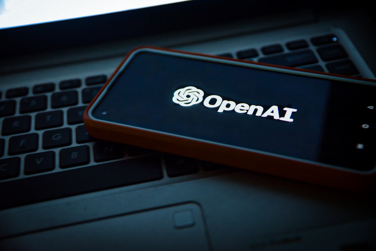 OpenAI on a phone beside a laptop keyboard