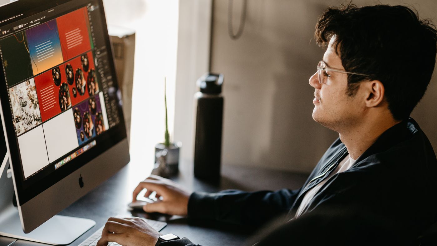 A graphic designer reviewing a colorful web layout on a desktop display