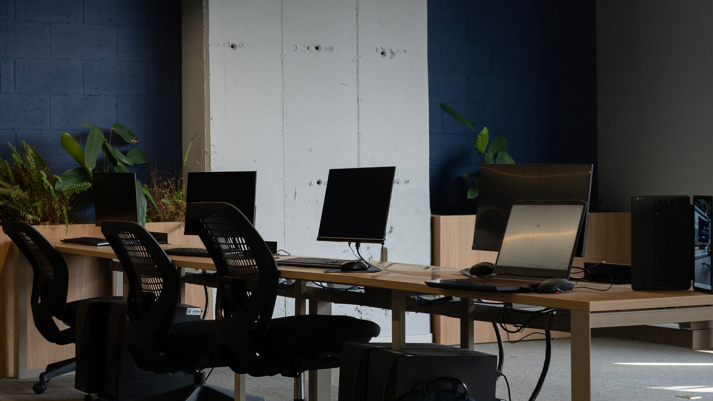 An empty contemporary coworking room with desks, monitors, and ergonomic chairs